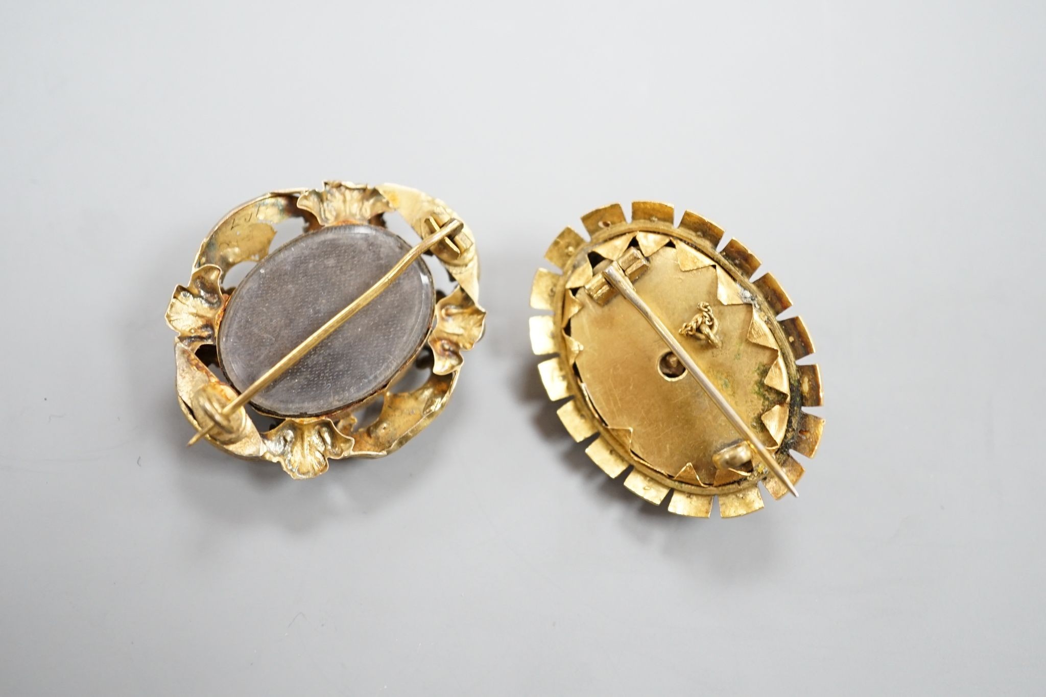 Two Victorian yellow metal and gem set oval brooches, including black enamel and split pearl, largest 34mm.